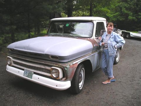 1984 Pontiac Fiero - A woman stands next to a 1960 Chevrolet C10 pickup truck with a primer-finished hood and a white bumper.