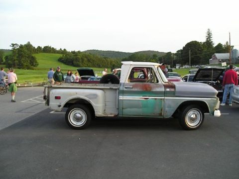 1984 Pontiac Fiero - A weathered pickup truck is parked in a lot with other vehicles and people milling around.
