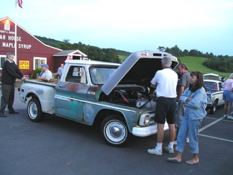 1984 Pontiac Fiero - A vintage pickup truck, likely from the late 1960s, is displayed with its hood open, drawing attention from onlookers.