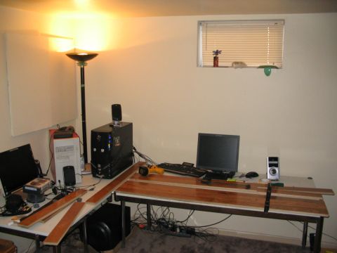 1986 Ford Bronco - A workspace is set up with multiple electronic devices and unfinished wood planks on a desk.
