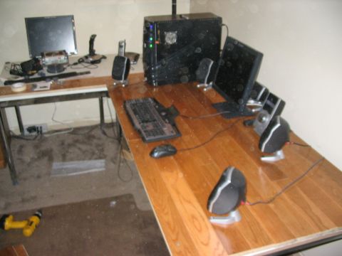 1986 Ford Bronco - A cluttered computer workstation features multiple monitors, a keyboard, mouse, speakers, and a desktop tower on a wooden desk.