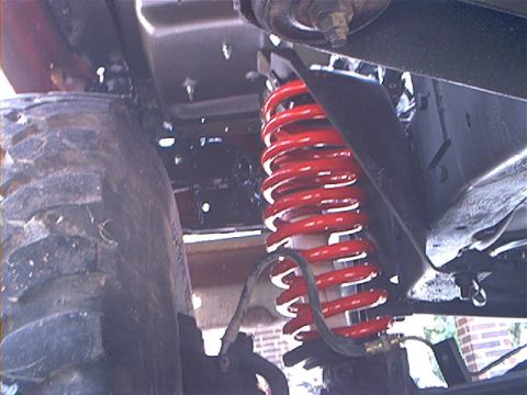 1978 Ford Bronco - The suspension system, including a bright red shock absorber, is visible next to a tire.