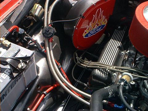1978 Ford Bronco - Close-up of an engine bay a red fan shroud with a Ford flame logo and chrome valve covers.