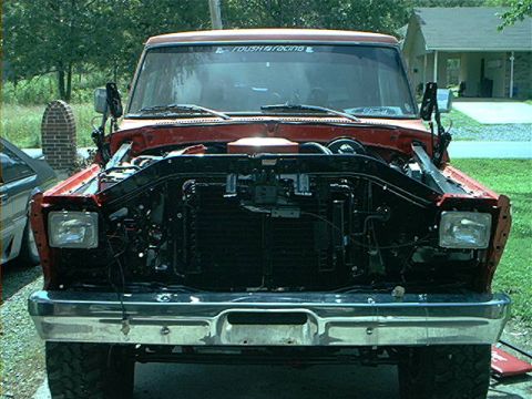 1978 Ford Bronco - The front of a red pickup truck is shown with its hood open, revealing the engine compartment.
