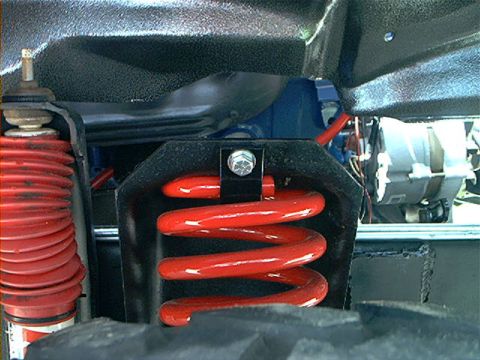 1978 Ford Bronco - Detailed view of a vehicle's suspension system, including a red coil spring and shock absorber.