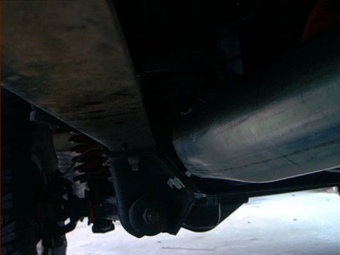 1978 Ford Bronco - A close-up view of a vehicle's undercarriage reveals suspension components and a large exhaust pipe.
