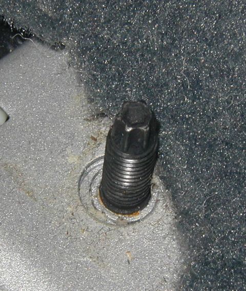 2000 Ford Taurus - Extreme close-up of a black threaded seat-mount stud standing up out of a car's painted floor pan, with light surface rust around the welde…