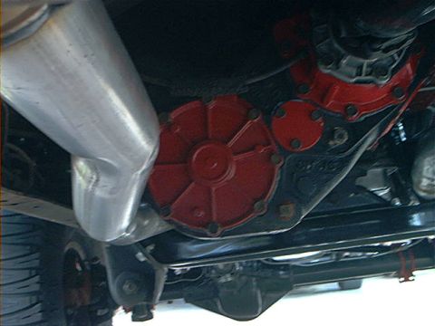 1978 Ford Bronco - Close-up view of the transfer case and exhaust system on the underside of a vehicle.