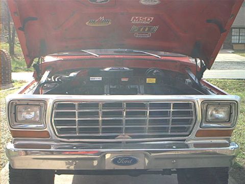 1978 Ford Bronco - Front view of a red 1978 Ford Bronco, hood raised to reveal the engine and various performance stickers.