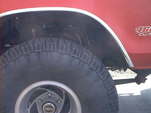 1978 Ford Bronco - Close-up of a red vehicle's fender and tire, showing '460 CU IN' badging.