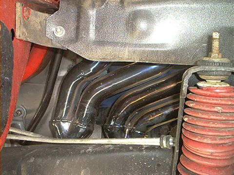 1978 Ford Bronco - The chrome exhaust manifold and red suspension spring are visible in this close-up shot.