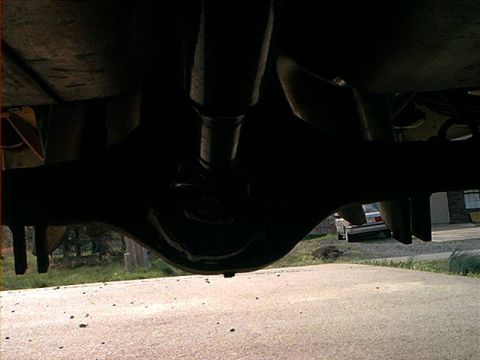 1978 Ford Bronco - Underside view of a vehicle's rear axle and driveshaft, with a distant vehicle visible in the background.