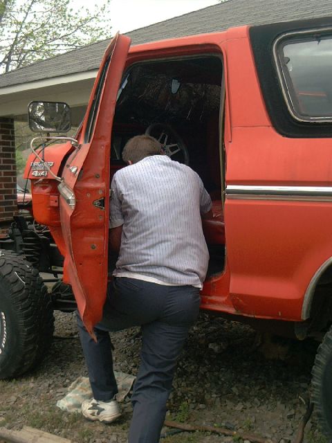 1978 Ford Bronco - A person enters the driver's side of a red SUV, possibly for maintenance or repair.