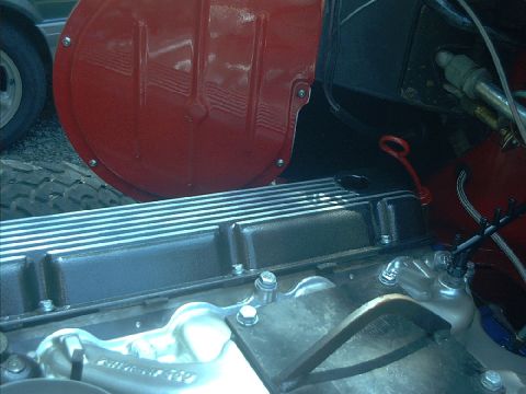 1978 Ford Bronco - Engine bay detail showing a valve cover and red fender liner, with a tire in the background.