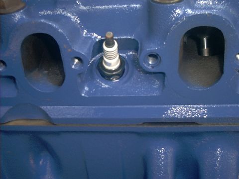 1978 Ford Bronco - Close-up view of a blue painted engine cylinder head, showing a spark plug and intake/exhaust ports.