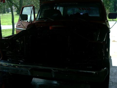 1978 Ford Bronco - The front of a red 1978 Ford Bronco is visible, with its hood removed and the driver's door ajar.