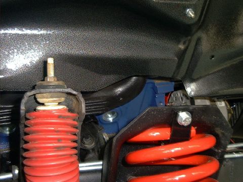 1978 Ford Bronco - Underside view of vehicle suspension with red coil springs and blue shock absorber components.