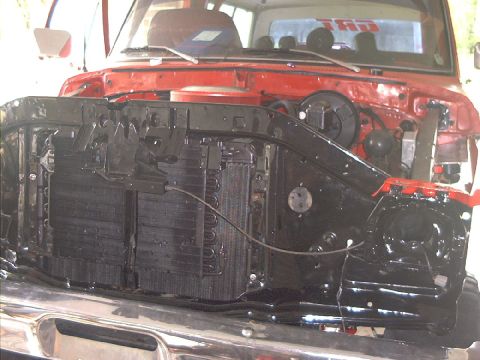 1978 Ford Bronco - The front end of a red truck is shown with the radiator and grille removed, revealing the internal components.