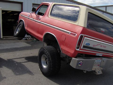 1978 Ford Bronco - This lifted Ford Bronco is parked at an angle outside a garage, showing off its off-road tires.