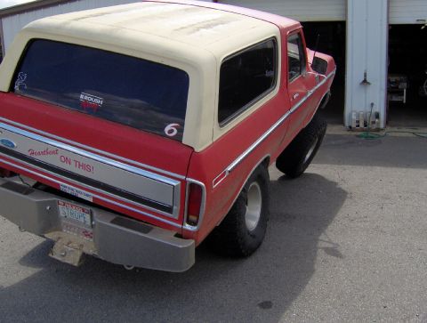 1978 Ford Bronco - A red and cream 1978 Ford Bronco is parked outside a garage with its rear quarter visible.