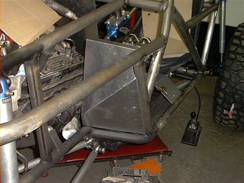 1978 Ford Bronco - Custom roll cage and engine bay of a project vehicle, with a large off-road tire in the background.