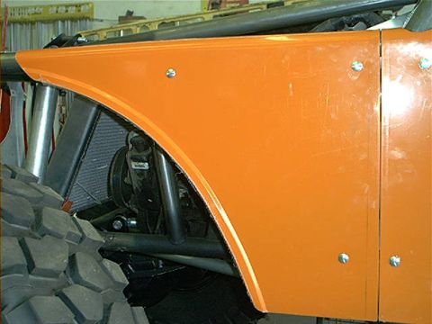 1978 Ford Bronco - Close-up of an orange fender and a massive tire on a custom off-road vehicle.