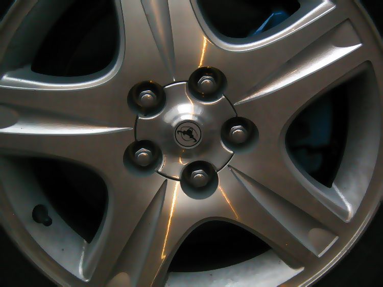 Close-up of a silver five-spoke alloy wheel with center cap and lug nuts