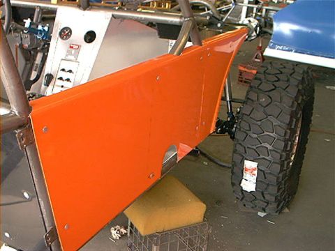 1978 Ford Bronco - A custom vehicle's orange side panel and large tire are visible in this close-up shot.