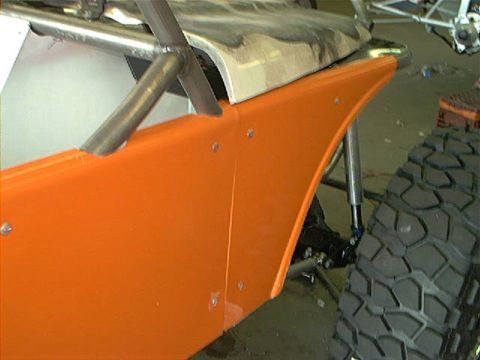 1978 Ford Bronco - Close-up of an orange fender and a large off-road tire on a custom vehicle project.