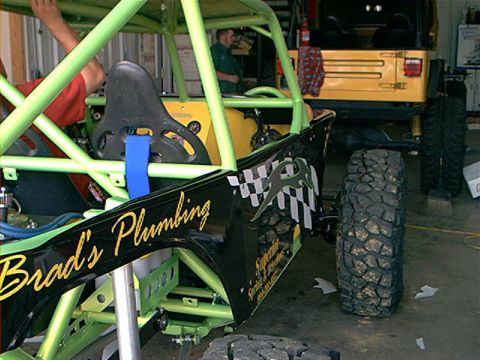 1978 Ford Bronco - A custom-built buggy with racing decals sits in a garage next to a yellow Jeep.