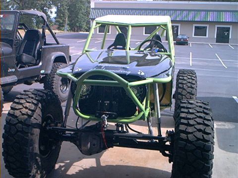1978 Ford Bronco - A custom-built off-road buggy with a prominent roll cage sits in a parking lot next to another vehicle.