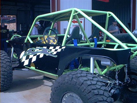 1978 Ford Bronco - Custom off-road buggy with a prominent roll cage and racing decals is shown in a workshop.