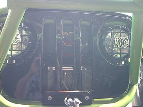 1978 Ford Bronco - A close-up view of a modified Jeep grille, equipped with auxiliary lights and a winch.