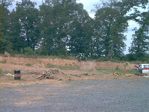 1978 Ford Bronco - A buggy navigates a dirt hill while a van sits nearby in a wooded area.