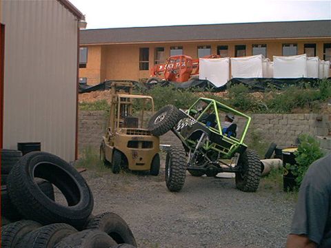 1978 Ford Bronco - A custom buggy is positioned precariously on a forklift, with a pile of tires in the foreground.