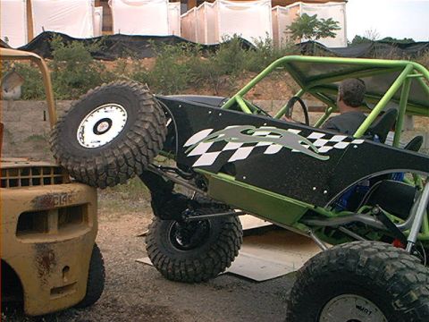 1978 Ford Bronco - A custom-built rock crawler buggy with a roll cage and large off-road tires is positioned next to a forklift.