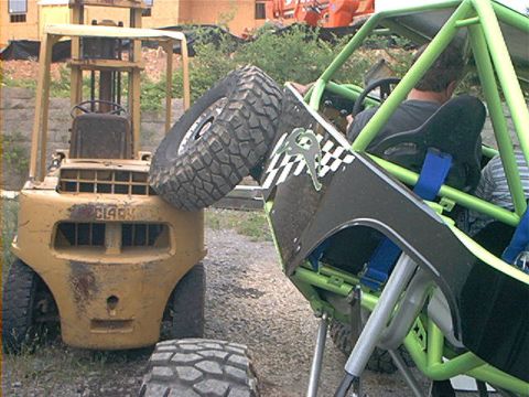 1978 Ford Bronco - A custom-built buggy is parked next to a forklift that is holding a large off-road tire.