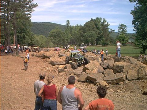 1978 Ford Bronco - A custom-built buggy is shown attempting to climb over a large rock formation during an off-road event.