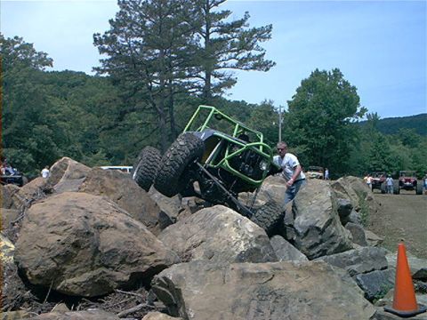 1978 Ford Bronco - A heavily modified rockcrawler navigates a challenging boulder course with a person guiding it.