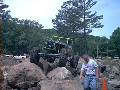 1978 Ford Bronco - A heavily modified Jeep navigates a challenging rock course, with spectators and other vehicles in the background.