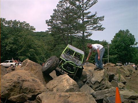 1978 Ford Bronco - An off-road vehicle navigates a challenging rocky terrain with spectators in the background.