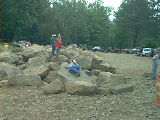 Off-road vehicles parked at a rock crawling event with people on rocks