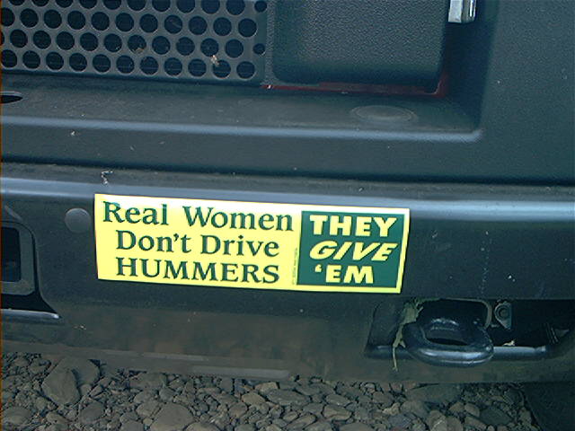 Rear bumper with two stickers. One says 'Real Women Don't Drive HUMMERS'. The other says 'THEY GIVE 'EM'
