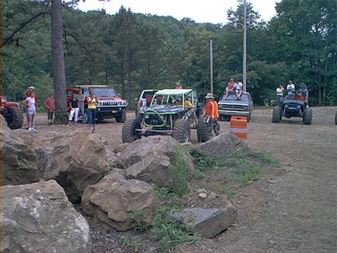 1978 Ford Bronco - People gather around modified off-road vehicles and SUVs in a rocky, outdoor area.