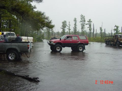 1995 Dodge 1500 - A red SUV navigates through a flooded area, with other trucks present in the scene.