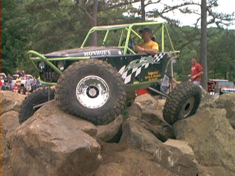 1978 Ford Bronco - A custom-built off-road buggy navigates a rocky terrain with a driver at the wheel.