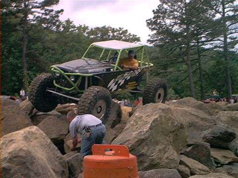 1978 Ford Bronco - A custom off-road buggy navigates a challenging rocky terrain with spectators in the background.