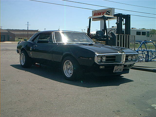 Black 1967 Pontiac Firebird coupe with chrome trim and aftermarket wheels parked on asphalt