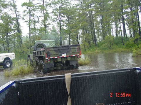1995 Dodge 1500 - Two trucks navigate a flooded, wooded area during what appears to be inclement weather.