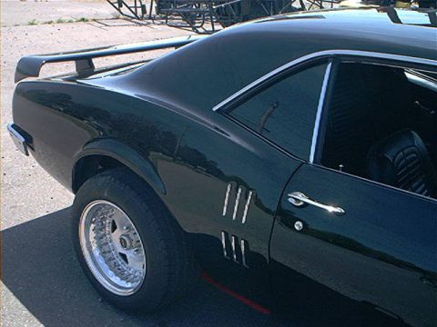 1978 Ford Bronco - This dark green coupe, likely a 1969 Firebird, is viewed from the rear three-quarter angle, showing its spoiler and side vents.